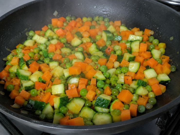 Tagliate a cubetti le carote e le zucchine. In una padella versate un cucchiaio di olio di oliva, aggiungete le verdure tagliate a dadini e i piselli, coprite con un coperchio e fate cuocere a fuoco medio per circa 15 minuti, girando di tanto in tanto e eventualmente aggiungendo un cucchiaio di acqua se le verdure dovessero tendere ad attaccarsi al fondo della padella. Salate poco prima del termine della cottura e lasciate raffreddare.