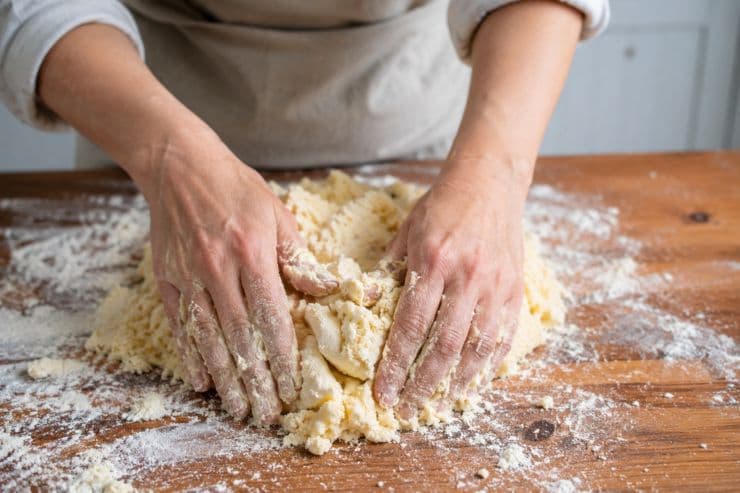 Prepariamo la pasta frolla mettendo su una spianatoia 500 grammi di farina, 200 grammi di zucchero, il burro a pezzetti, il lievito, una bustina di vanillina e la scorza grattugiata del limone. Uniamo un uovo alla volta e amalgamiamo gli ingredienti con la punta delle dita, senza lavorare e scaldare troppo la pasta. Avvolgiamo la pasta frolla in una pellicola da cucina e facciamola riposare in frigorifero per circa 20 minuti.