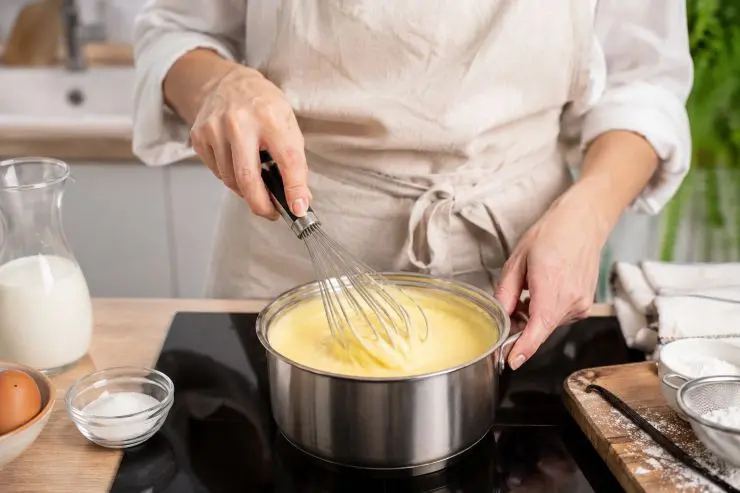 Nell’attesa prepariamo la crema mescolando i tuorli con 200 grammi di zucchero, 150 grammi di farina e la bustina di vanillina. Il composto così ottenuto va mescolato pian piano al latte caldo e messo in un pentolino posto sul fuoco a fiamma bassa. Aggiungiamo un pezzo di scorza di limone, che andrà poi eliminato, e mescolate continuamente fino a quando la crema non si sarà addensata.