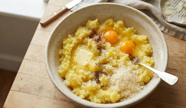 Una volta che le patate sono cotte scolatele e, quando sono ancora calde, privatele della buccia, dopodiché passatele nello schiacciapatate avendo cura di far cadere il composto così ottenuto in un’ampia ciotola. Aggiungete il burro, due uova, il sale, il pepe, la noce moscata e il formaggio grattugiato. Mescolate bene il tutto.