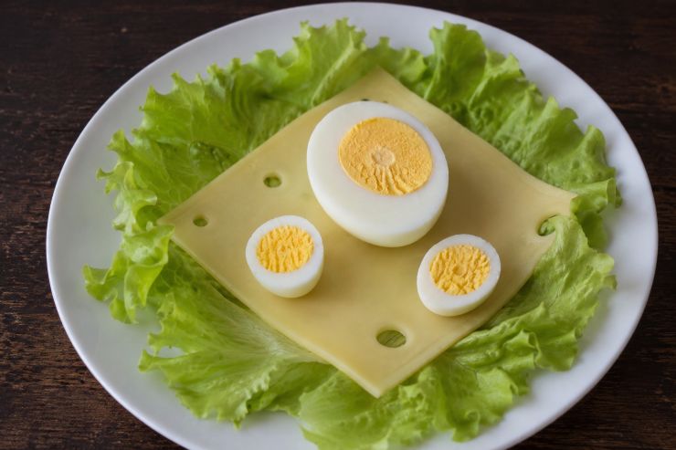 In ciascun piatto ponete una foglia di lattuga e al centro una fetta di Emmentaler. Al centro del piatto posizionate poi mezzo uovo sodo di gallina e due mezze uova sode di quaglia.