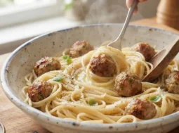 piatto di spaghetti fumanti con polpette di carne cotte al forno, basilico fresco e parmigiano in una ciotola di ceramica artigianale
