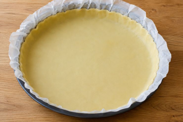 Stendete la pasta brisé su una teglia da forno, preferibilmente quella che si utilizza per la crostata, rivestita di carta forno. Con un altro foglio di carta forno coprite la pasta brisè e versate all’interno dei legumi secchi, per evitare rigonfiamenti durante la cottura. Infornate a 180 °C per 10 minuti.
