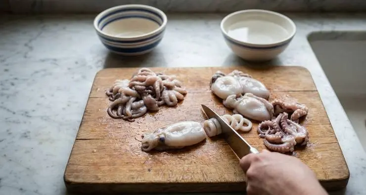 Pulite i moscardini, lavateli bene sotto acqua corrente fredda e metteteli a scolare. Staccate la sacca e affettatela a rondelle, dopodiché tagliate ogni tentacolo in tre pezzi.