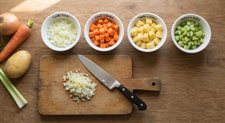 Iniziate con il tagliare tutte le verdure: tritate finemente la cipolla; sbucciate la carota, eliminate le due estremità e tagliatela a dadini; sbucciate la patata e tagliatela a dadini; tagliate a dadini la costa di sedano.
