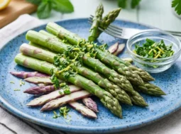 Piatto di asparagi verdi e viola cotti al vapore con scorza di limone e menta fresca, rimedio naturale contro la ritenzione idrica.