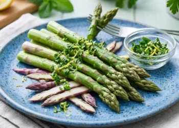 Piatto di asparagi verdi e viola cotti al vapore con scorza di limone e menta fresca, rimedio naturale contro la ritenzione idrica.