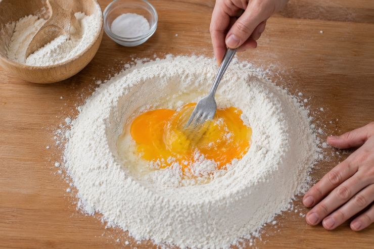 Su una spianatoia disponete a fontana la farina precedentemente setacciata. Al centro rompete le uova e, dopo aver aggiunto il sale, iniziate a sbatterle con una forchetta, incorporando a poco a poco la farina circostante.