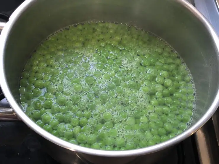 Aggiungete i piselli, salate, pepate, coprite e cuocete per circa 15-25 minuti, aggiungendo se necessario qualche cucchiaio di acqua calda. Nel frattempo tritate finemente il prezzemolo e la menta e aggiungeteli un paio di minuti prima della fine della cottura, tenendone da parte una manciata.
