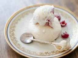 Mini pavlova con gelato guarnita con lamponi freschi servita su un piatto elegante.