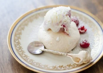 Mini pavlova con gelato guarnita con lamponi freschi servita su un piatto elegante.
