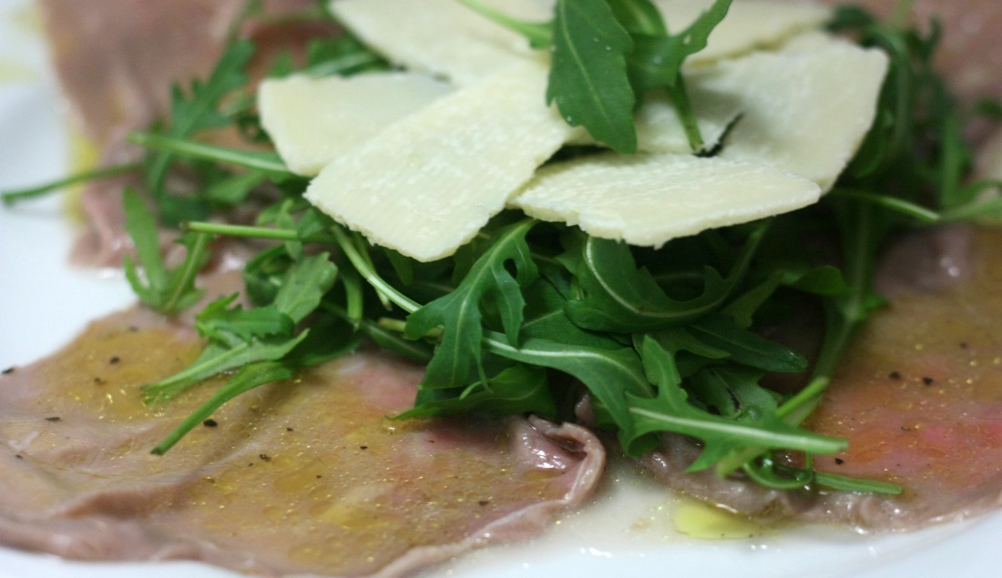 Carpaccio di carne con rucola e scaglie di Parmigiano Reggiano