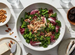 Composizione di alimenti ricchi di calcio: insalata di broccoli e kale, mandorle, sarde, parmigiano e ceci su tavola bianca.