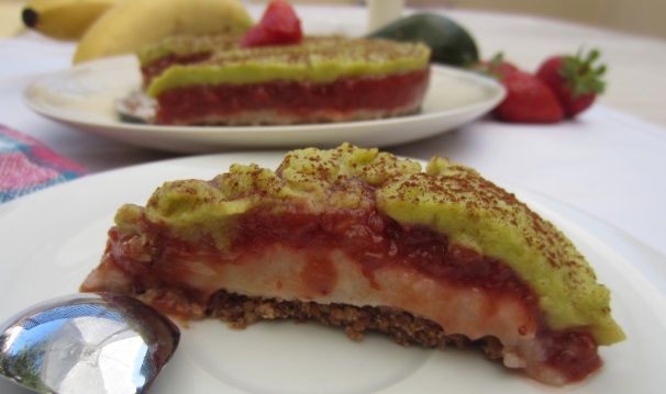 Cospargete con il cacao amaro, decorate e servite la vostra deliziosa torta crudista con fragole, banane e avocado.