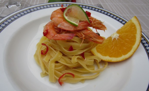 Servite le tagliatelle agli agrumi e mandorle decorando il piatto con una fetta di lime, una fetta di arancia e cospargendo il tutto con il peperoncino piccante fresco.