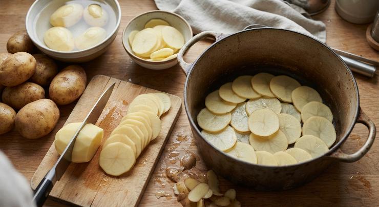 Preparate la verdura. Sbucciate le patate, lavatele ed affettatele. Disponete le fette sul fondo di una pentola capiente.