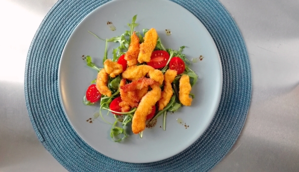 Le pepite di pollo alla paprika con rucola e pomodorini sono pronte per essere servite ai vostri commensali.