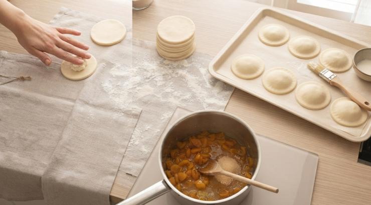 Ricopriteli con i dischetti rimasti, facendo pressione per far uscire tutta l’aria. Sigillate i bordi. Sistemate i ravioli su una teglia da forno foderata con carta da forno e spennellate la superficie dei ravioli con il latte. Infornate a 180 gradi per 15 minuti. Nel frattempo preparate la salsa di albicocche. Tritate le albicocche dopo averle strizzate. Trasferitele in una padella insieme allo zucchero rimasto e 2 a cucchiai di acqua, quindi lasciatele cuocere per 10 minuti. Le albicocche si disfaranno trasformandosi in una salsa dolce e vischiosa. Sfornate i ravioli quando sono dorati in superficie.