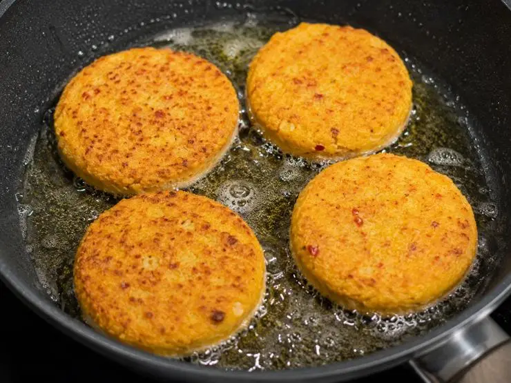 Versate un po’ di farina gialla di mais rimasta sul piatto ed appoggiate la polpetta sulla farina. Schiacciate delicatamente con le dita, dando così al composto la forma di un hamburger. Versate l’olio nella padella e fatelo riscaldare. Friggete l’hamburger circa 3 minuti da ogni lato. Prima di servirlo appoggiatelo sulla carta assorbente per eliminare l’eccesso di olio.&nbsp;