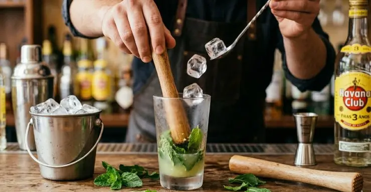 Mettete in fondo le foglie di menta fresca, circa 6-7, e pestate tutto con un pestello per amalgamare bene i sapori. Ora aggiungete i cubetti di ghiaccio.