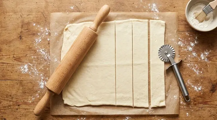 Srotolate la pasta sfoglia e stendetela con il mattarello per assottigliarla leggermente. Dividetela in quattro strisce più o meno delle stesse dimensioni.