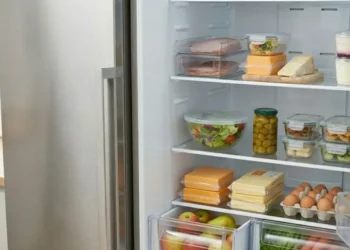 Interno di un frigorifero moderno e pulito con gli alimenti sistemati correttamente sui ripiani e frutta e verdura nei cassetti inferiori