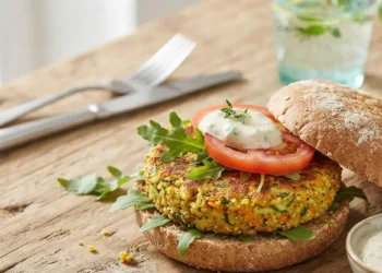 Hamburger vegetale di miglio e verdure servito su pane integrale con salsa e rucola