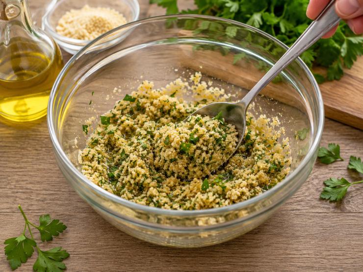 Mettete in una terrina del pane grattugiato, aggiungete dell’olio extravergine di oliva e del prezzemolo, poi mescolate bene per amalgamare gli ingredienti.
