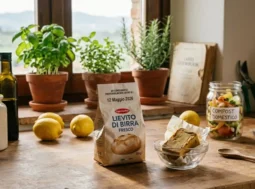 Composizione su tavolo rustico con panetto di lievito di birra fresco scaduto nel 2026, piante aromatiche in vaso, limoni e un barattolo per il compostaggio domestico.