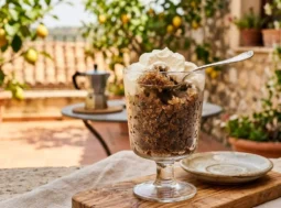 Ricetta granita al caffè estiva Granita al caffè fatta in casa servita in un bicchiere di vetro con panna montata su una terrazza estiva