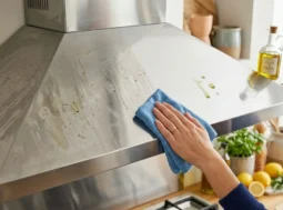 Trucco per lucidare la cappa in acciaio satinato Confronto prima e dopo della pulizia di una cappa in acciaio satinato in cucina con un panno e olio d'oliva.