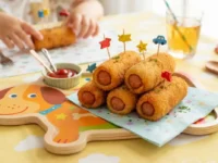 Rollini di wurstel croccanti e dorati serviti su un piatto colorato a misura di bambino, pronti da gustare