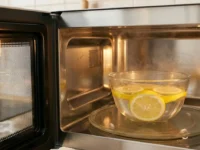 Pulizia del forno a microonde con ciotola di acqua e fette di limone per eliminare il cattivo odore