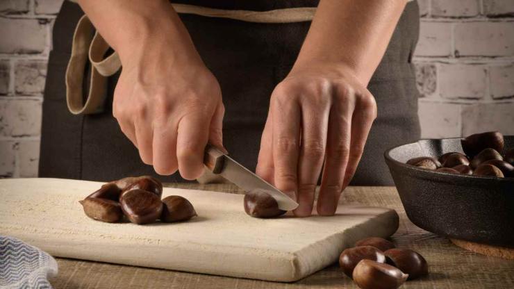 Fatto ciò vedrete che la buccia esterna si sarà ammorbidita e sarà più facile da rimuovere: procedete fino a terminare le castagne, quindi trasferitele in una pentola ampia. Aggiungete acqua fredda fino a coprirle completamente, unite una foglia di alloro, una presa di sale ed un pizzico di zucchero: coprite parzialmente la pentola con il coperchio e portate ad ebollizione a fuoco dolce.