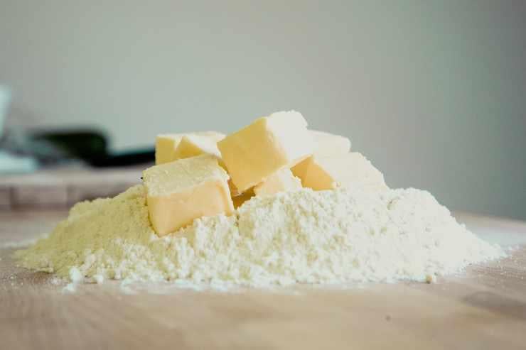 Iniziate preparando la frolla: versate la farina su un piano, aggiungete il burro freddo a cubetti e lavorate con la punta delle dita fino ad ottenere un composto sabbioso. Unite poi zucchero, uova, scorza di limone e sale ed impastate velocemente fino a formare un panetto liscio. Avvolgetelo nella pellicola e lasciatelo riposare in frigorifero per almeno 30 minuti.