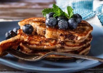Per pancakes alti e soffici, il trucco principale è non lavorare troppo la pastella: mescolate il minimo indispensabile. Un altro trucco è lasciar riposare l'impasto 10 minuti prima di cuocerlo: il lievito inizia ad agire ed i pancakes cresceranno meglio. Se volete evitare che le gocce di cioccolato affondino, passatele prima in un cucchiaino di farina. In padella, mantenete una fiamma medio bassa: una temperatura troppo alta li brucia fuori e li lascia crudi dentro. Per una versione ancora più leggera, potete sostituire parte del latte con acqua o usare latte vegetale (soia, avena, mandorla). Varianti golose: aggiungete un cucchiaino di cacao alla pastella per pancakes "double chocolate", oppure un po' di cannella per dare un tocco natalizio. Se volete una consistenza più soffice, aggiungete un cucchiaio di yogurt. Se invece preferite pancakes più spessi, diminuite leggermente il latte. Per una colazione speciale, provate a servirli con: pere caramellate, frutti rossi, crema di nocciole, sciroppo d'acero caldo. pancakes veloci morbidi senza uova burro con gocce di cioccolata ricette.com