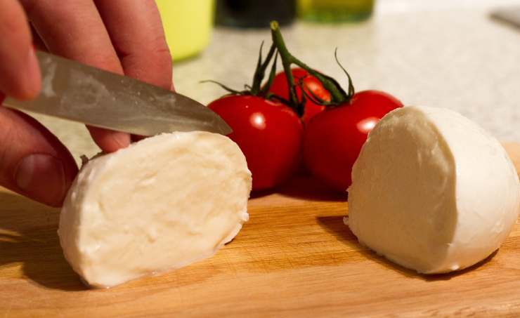 Iniziate tagliando la mozzarella a pezzetti e trasferendola in un colino in modo che possa sgocciolare molto bene. Versate la passata di pomodoro in una ciotolina e conditela con un po’ di sale, mescolate e mettetela da parte. Tagliate a striscioline il prosciutto cotto e mettete da parte anche questo. Fatto ciò preparate l’impasto: versate in una ciotola capiente la farina e il lievito istantaneo, mescolate bene quindi aggiungete poco alla volta l’acqua ed amalgamate tutto con una forchetta.