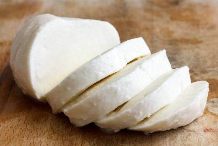 Intanto tagliate la mozzarella a fettine e fatela sgocciolare molto bene: ideale sarebbe lasciarla in frigorifero per qualche ora in modo che possa asciugarsi quanto più possibile. Una volta terminata la cottura del sugo, spegnete e lasciatelo raffreddare: passate quindi alle melanzane. Sciacquatele e strizzatele, poi asciugatele molto bene tamponandole con un canovaccio pulito. A questo punto versate un po’ di olio di semi in una padella dai bordi alti e scaldatelo bene.