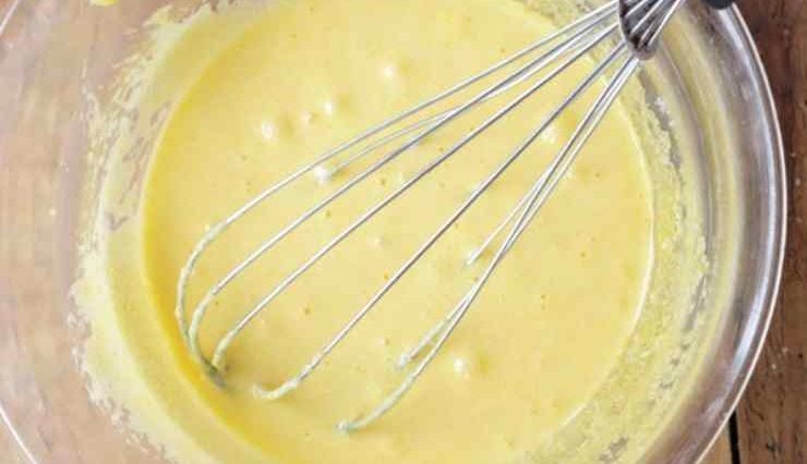 Unite il burro fuso ed intiepidito, il latte, la buccia grattugiata di limone e la cannella quindi mescolate ancora in modo da ottenere un composto omogeneo. Setacciate insieme la farina ed il lievito in polvere per dolci, quindi uniteli poco alla volta al resto degli ingredienti sempre amalgamando bene. A questo punto unite anche le mele dopo averle sgocciolate bene, ma procedete con grande delicatezza perché potrebbero rompersi: dovranno essere completamente avvolte da uno strato sottile di impasto.