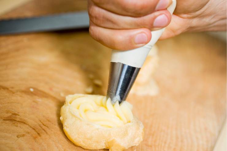 In una scodella a parte, sbatti le uova con delle fruste elettriche e poi incorporale un poco alla volta al composto ormai tiepido. Quando avrai ottenuto un impasto colloso ed omogeneo, trasferiscilo in una sac à poche e forma delle montagnette su una teglia ricoperta con uno strato di carta da forno, distanziandole di circa 3 cm le une dalle altre.