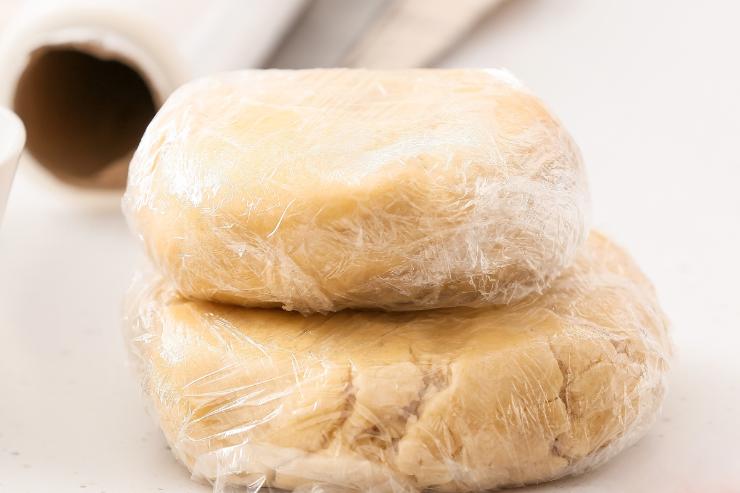 Sposta il composto su un piano di lavoro infarinato e continua ad impastare finché non avrai ottenuto un panetto liscio ed omogeneo. Avvolgilo con la pellicola trasparente e lascialo riposare in frigo per circa 30 minuti. Così facendo, diventerà più facile stendere i biscotti.