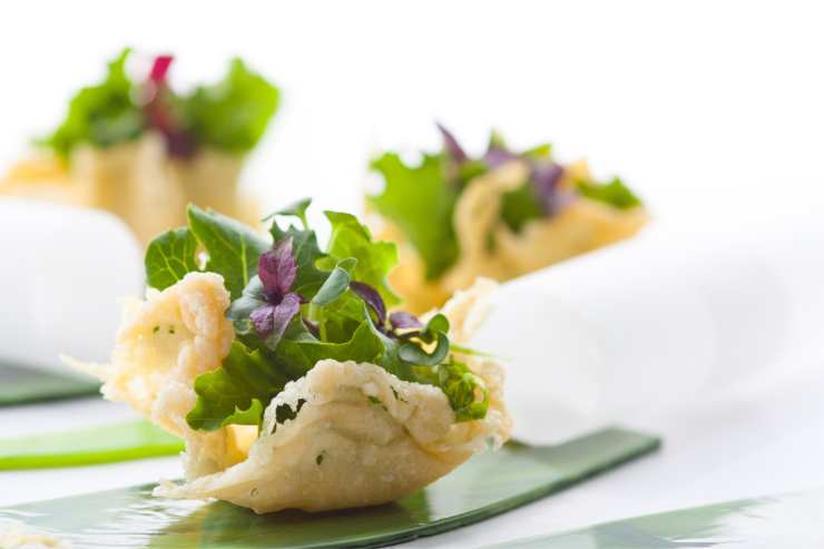 Lascia che i cestini di parmigiano si solidifichino e poi sfila la carta da forno, estrai i cestini dal bicchiere e farciscili a piacere. In questo caso, mettici uno spicchio d’uovo sodo ed un’insalatina con rucola e ravanelli tagliati sottilmente. Condisci tutto con sale, pepe e olio extravergine d’oliva e porta in tavola.