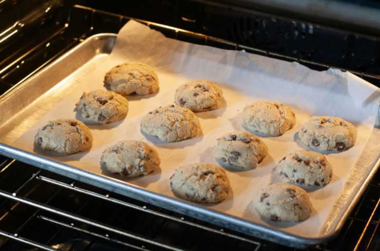 Stacchiamo ora dei pezzi di composto e lavoriamo prima a dare una forma di pallina e poi schiacciando: così otterremo la classica forma tonda dei biscotti. Sistemiamoli tutti in una teglia da forno foderata;