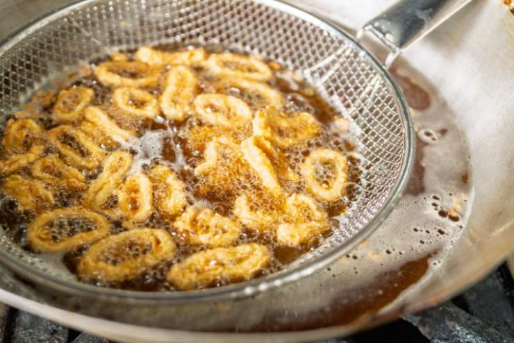 Riversiamo la farina in una ciotola e usiamola per impanare i nostri anelli di calamari. Spolveriamo via eventuale farina in eccesso. Scaldiamo l’olio per friggere in una padella capiente e una volta caldo immergiamo i calamari;