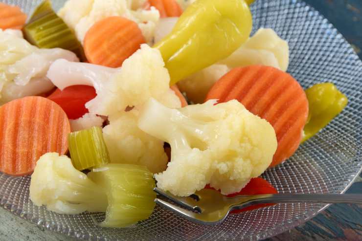 Nel frattempo, metti in ammollo le acciughe in acqua fredda per 10 minuti e pulisci le papacelle e tagliale a fettine sottili. Denocciola, poi, le olive e scola la giardiniera, tagliando gli ingredienti più grandi a pezzettini. Riprendi le acciughe, asciugale, elimina la lisca e tagliale a pezzetti.