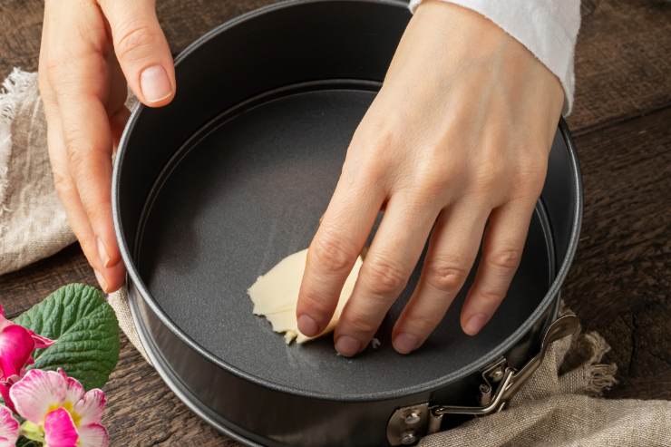 Prendi uno stampo rotondo grande 20 cm di diametro ed imburralo ben bene. Adagiaci sopra un foglio d’ostia e copri i bordi con una striscia di carta da forno. Rovescia quindi il composto all’interno dello stampo, livella la superficie e spolvera tutto con lo zucchero a velo. 