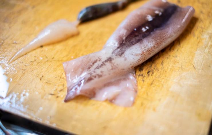 Si può dire che la parte più complicata dell’intera ricetta è la pulizia dei calamari: una volta tolti i tentacoli andiamo ad eliminare anche gli occhi e le interiora. Rimuoviamo la cartilagine e spelliamoli (la pelle dovrebbe venir via facilmente tutta insieme). Una volta “nudi”, andiamo a sciacquare per bene i calamari e poi sgoccioliamoli con cura;