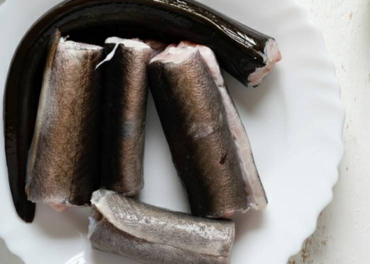 Iniziamo dalla pulizia dei capitoni, la parte forse più lunga e noiosa: tagliamo via la testa e anche la coda. Procediamo a eviscerarli e sciacquiamoli con cura sotto l’acqua corrente. Sgoccioliamoli per bene e andiamo a tagliarli a pezzi più piccoli, lunghi 4/5 centimetri circa. Tamponiamo eventuale acqua in eccesso con della carta assorbente o con un canovaccio pulito;.