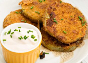 pomodori fritti su tagliere con ciotola di salsa bianca