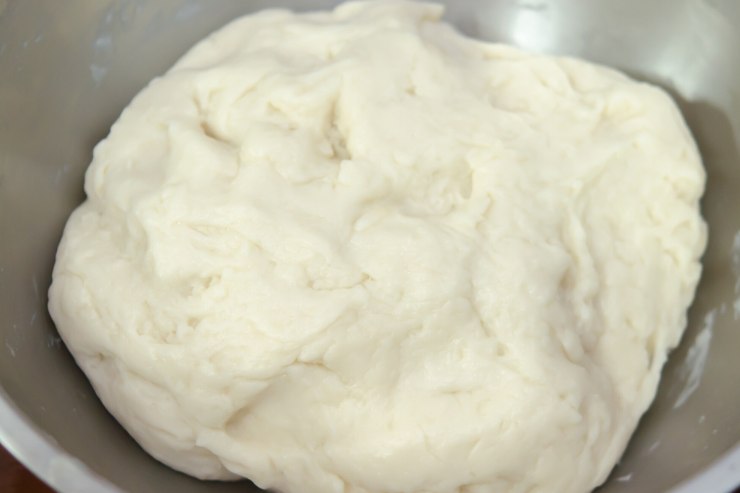 Per preparare la pasta choux inizia a portare a bollore un pentolino con dentro acqua, burro, sale e zucchero. Dopodiché, unisci la farina tutta in una volta e mescola velocemente con un mestolo di legno, fino a quando il composto non avrà acquisito consistenza e non sarà diventato una palla omogenea che si stacca dalle pareti. Toglilo quindi dal fuoco e lascialo intiepidire.